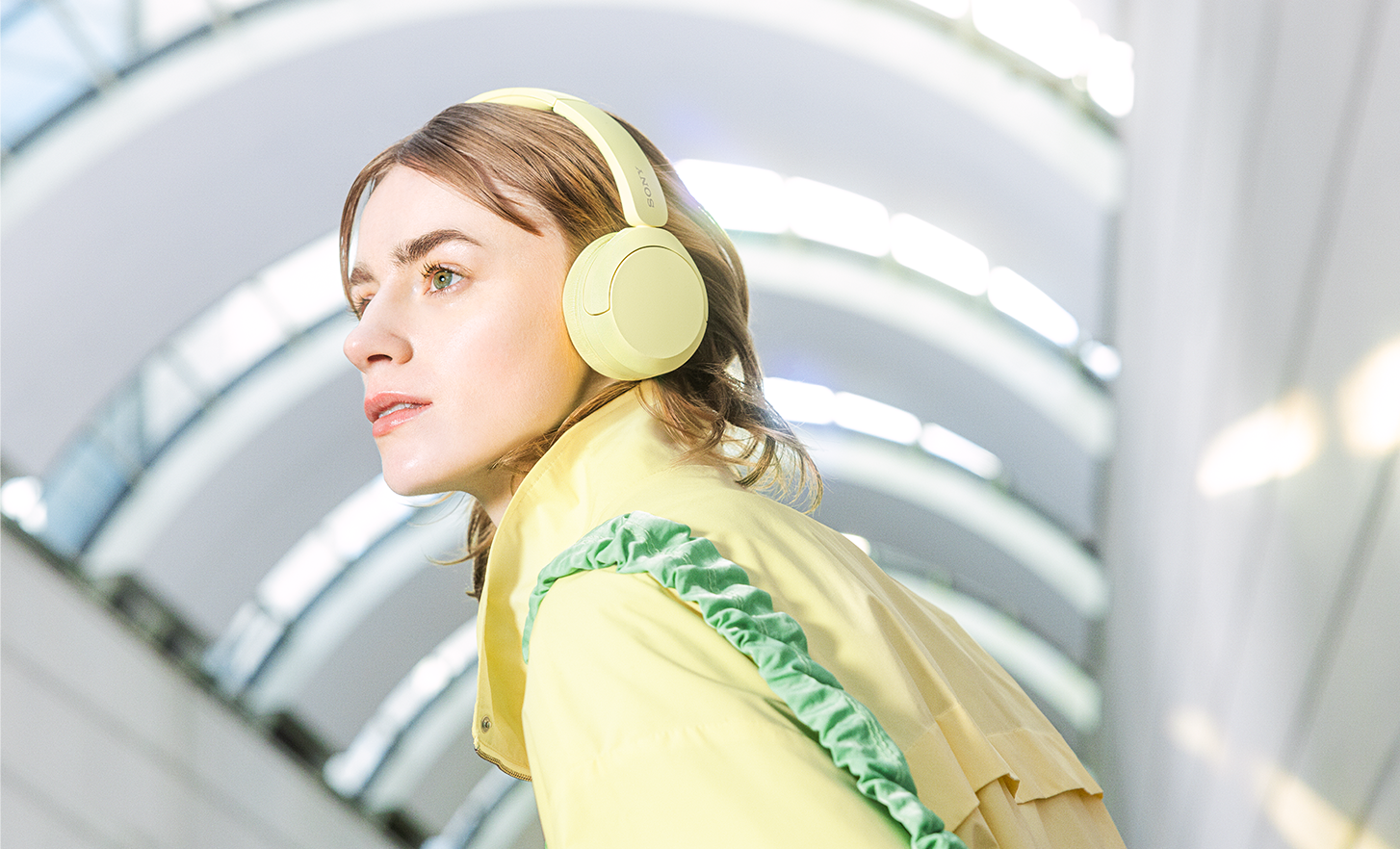 Person wearing a pair of yellow Sony WH-CH520 headphones and a matching stylish jacket.
