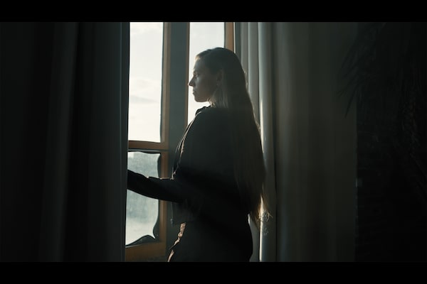 Example image of a woman looking at scenery outside a window, her form silhouetted between two curtains
