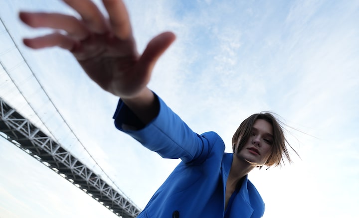 Wide-angle portrait of woman with part of suspension bridge span in background