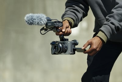Usage image of a videographer holding the FX2 equipped with an XLR handle and microphone while filming a video