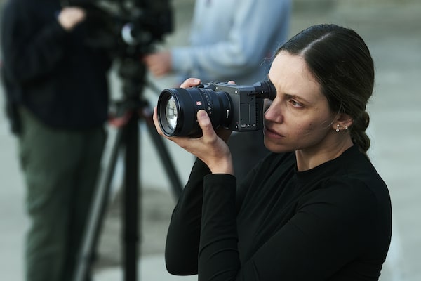 Usage image of a videographer taking photos in the foreground with two videographers filming video in the bokeh background