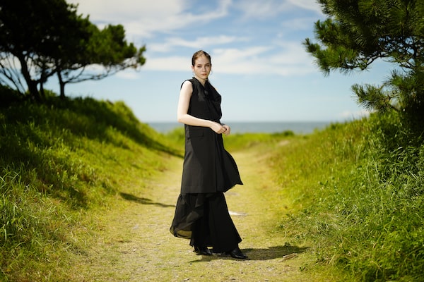 Image of a woman with beautiful bokeh, standing in a path to a beach