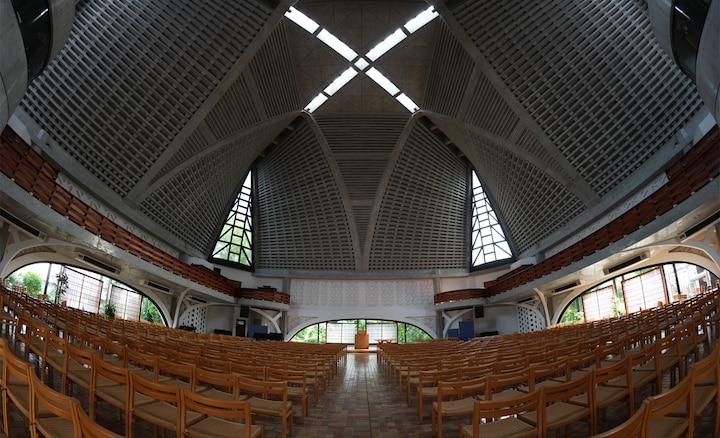 Diagonal fisheye view of an architectural interior, capturing intricate ceiling patterns with sharp detail across the frame, while foreground chairs curve naturally toward the edges