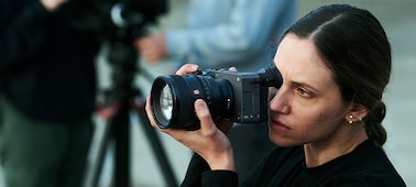 Usage image of a videographer taking photos in the foreground with two videographers filming video in the bokeh background