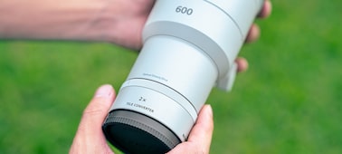 Super-telephoto lens with a 2.0x teleconverter attached, held in hand