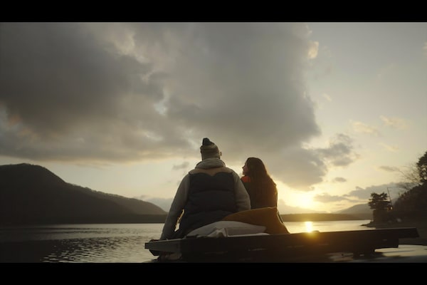 Image of two people sitting close to each other, with an evening scene in background