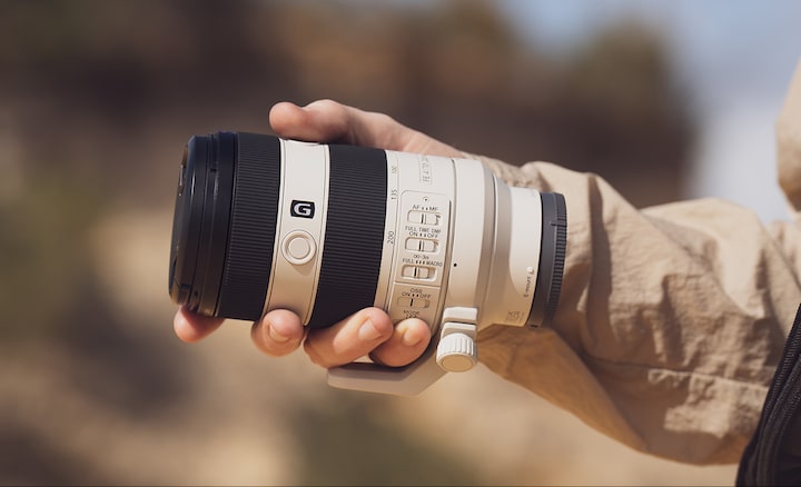 Usage image showing lens body held in palm of user&rsquo;s hand, emphasising compact size
