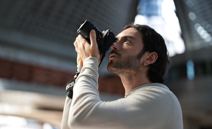 Person holding a camera with the FE 8-14mm F3.5 Fisheye G lens attached, showing the lens's compact size